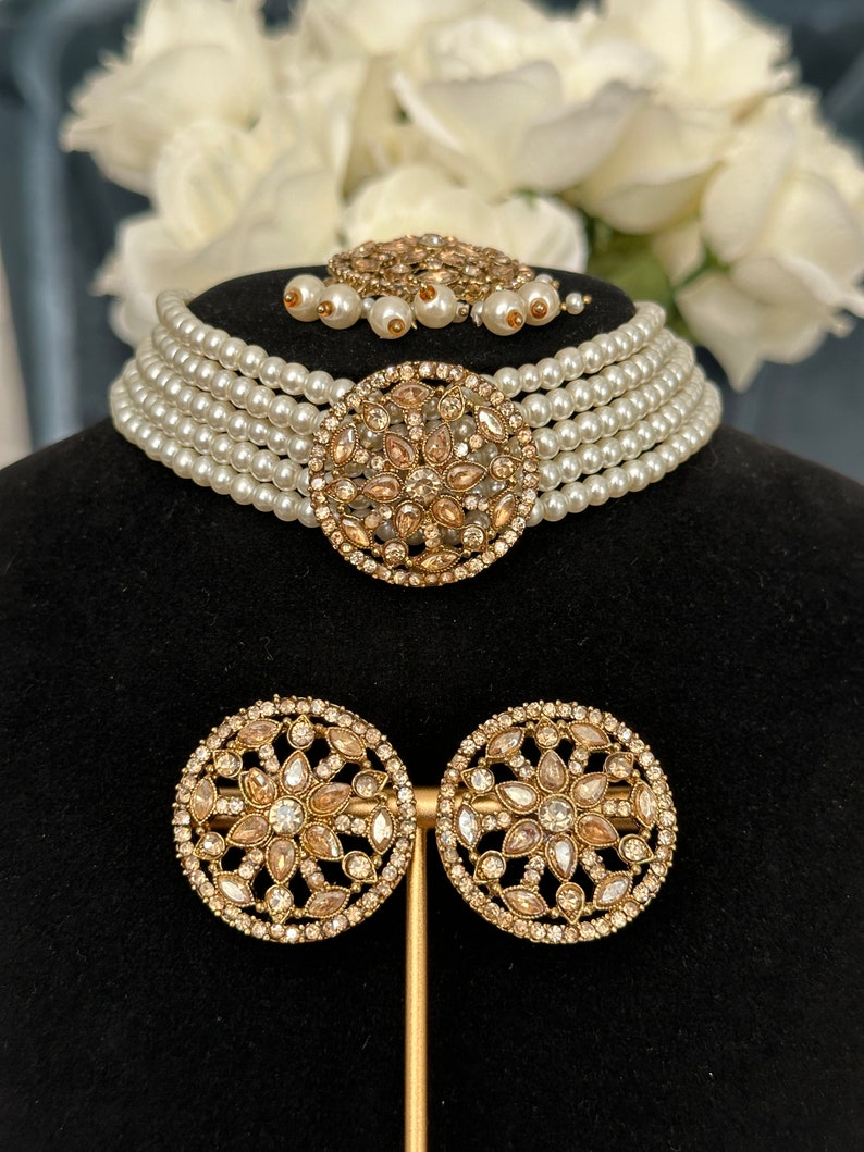 this choker has off-white pearls and paired with gold stonework on earrings, centrepiece and tikka