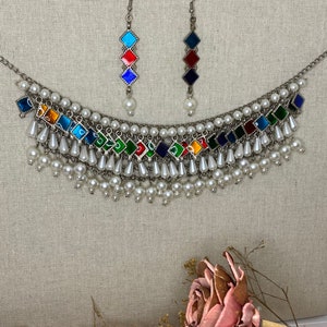 Peut inclure: Un collier en argent avec un motif en &eacute;mail multicolore et des accents de perles blanches. Le collier a un design en couches avec plusieurs rang&eacute;es de perles. Le collier est assorti &agrave; des boucles d'oreilles avec un design en &eacute;mail multicolore similaire.
