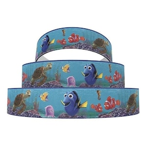 May include: Three rolls of blue ribbon with a Finding Nemo theme. The ribbon features images of Dory, Nemo, sea turtles, and seahorses.