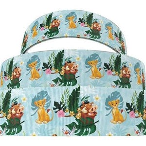 May include: Three rolls of blue ribbon with a repeating pattern of cartoon lions, warthogs, and tropical leaves.
