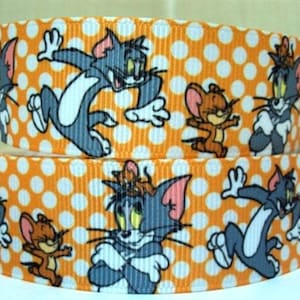 May include: Orange and white ribbon with a polka dot pattern featuring Tom and Jerry cartoon characters. The ribbon has a repeating pattern of Tom and Jerry in various poses.