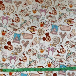 May include: White fabric with a repeating pattern of cartoon characters, including Mickey Mouse, Minnie Mouse, Donald Duck, and Goofy. The fabric features a variety of colors, including pink, red, blue, and yellow. The fabric also includes the text "Small World" and "I'd rather be at Disney".