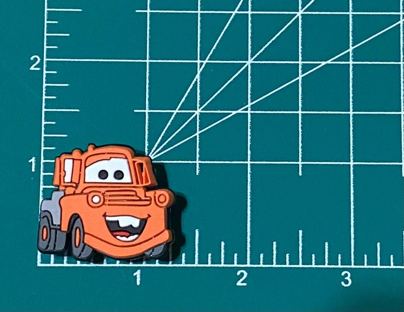 May include: Orange and gray cartoon tow truck with a smiling face. The tow truck is a character from the Disney Pixar movie Cars.