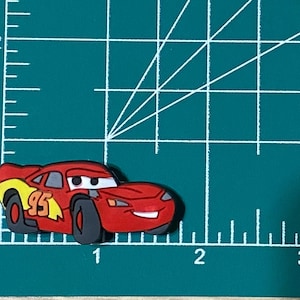 May include: Red and yellow cartoon race car with the number 95 on the side. The car has a smiling face and black wheels.