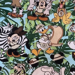 May include: A fabric pattern featuring various Disney characters in safari attire, including Mickey Mouse, Donald Duck, and Pluto, set against a backdrop of green tropical leaves and a light blue background. The design includes zebras and elephants.