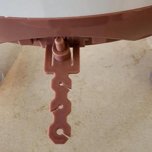 May include: A close-up of a pink plastic shower head with a lever to adjust the water flow. The shower head is attached to a curved, pink plastic arm.