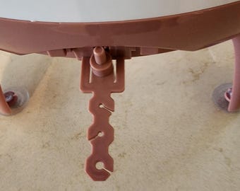 May include: A close-up of a pink plastic shower head with a lever to adjust the water flow. The shower head is attached to a curved, pink plastic arm.