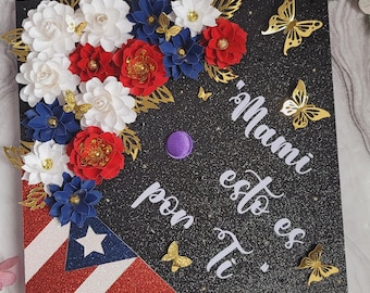 May include: A black graduation cap decorated with red, white, and blue paper flowers, gold butterflies, and the Puerto Rican flag. The text "Mami esto es Ti" is written in white script.
