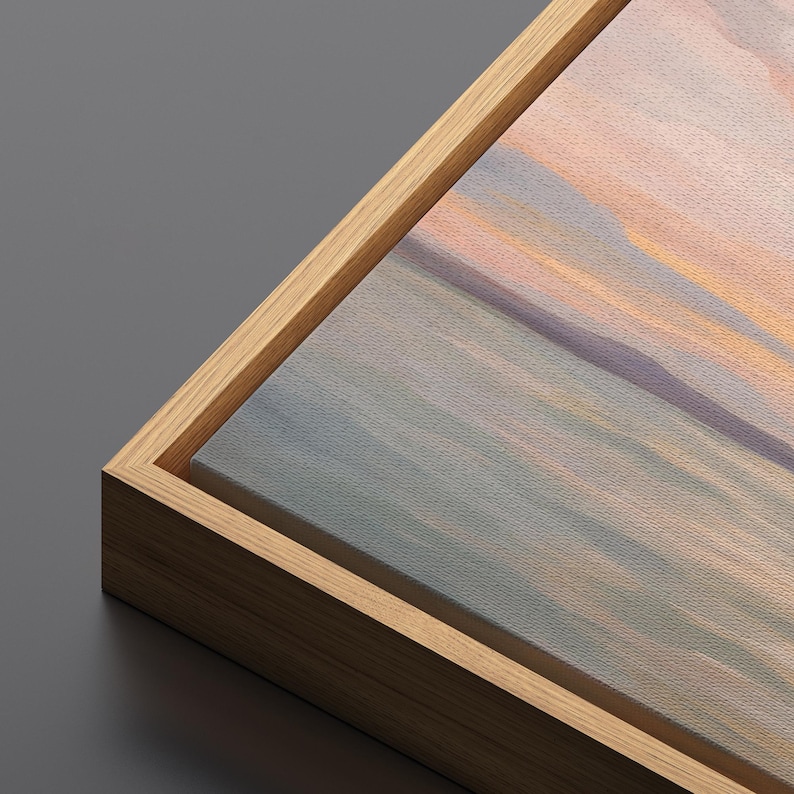 May include: A corner view of a canvas art print with a natural wood frame. The artwork features a soft, abstract landscape in shades of blue, peach, and lavender. The frame is a light brown color, and the canvas has a textured appearance.