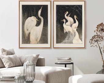 May include: Two framed prints of white egrets on a black background. The print on the left shows two egrets standing close together. The print on the right shows five egrets standing in a group.