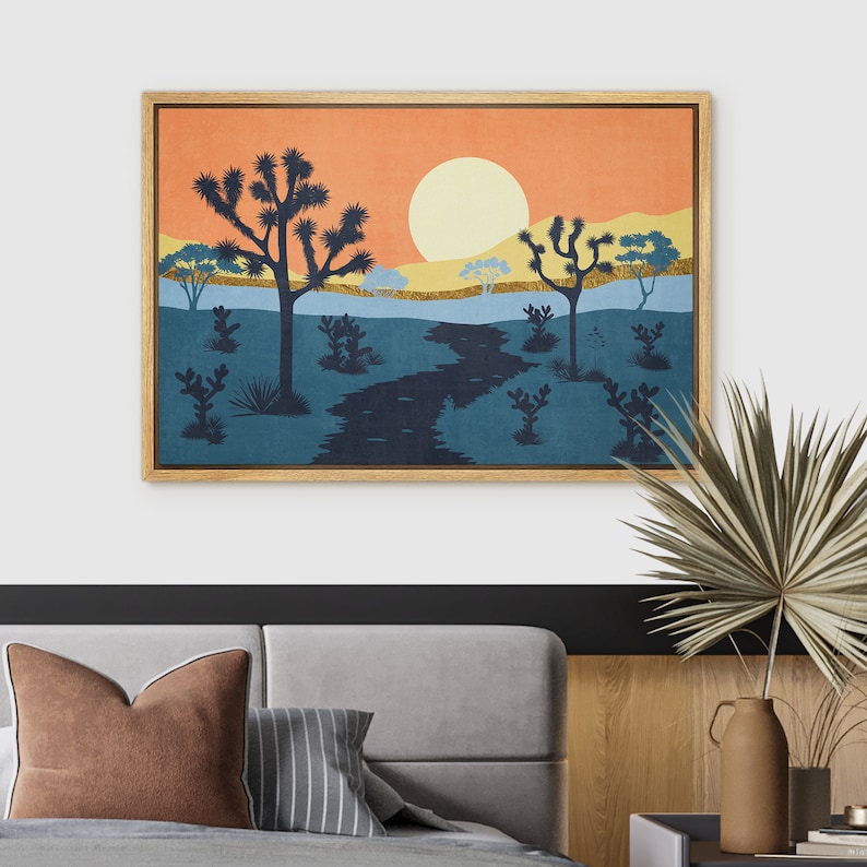 K&ouml;nnte beinhalten: Ein gerahmter Druck eines W&uuml;stenlandschafts mit untergehender Sonne, einem gewundenen Fluss und silhouettierten Joshua-B&auml;umen. Der Druck hat eine Vintage-&Auml;sthetik mit einer warmen Farbpalette aus Orange, Gelb, Blau und Gr&uuml;n.