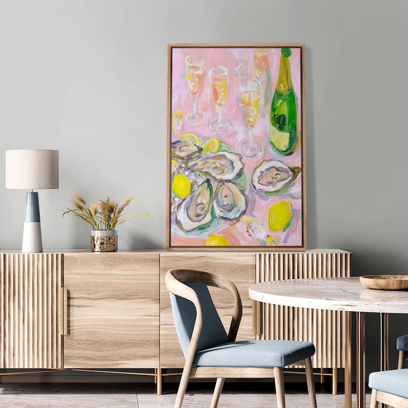 May include: An abstract painting of a dining scene with oysters, champagne, and lemons. The artwork features a pink background, a green champagne bottle, and several champagne flutes. The oysters are arranged on a plate with lemon slices.