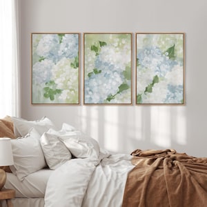 Puede incluir: Tres impresiones art&iacute;sticas florales enmarcadas. Cada impresi&oacute;n presenta flores de hortensia en tonos azules, blancos y verdes. La obra de arte est&aacute; sobre un fondo verde claro, con un marco de madera natural.