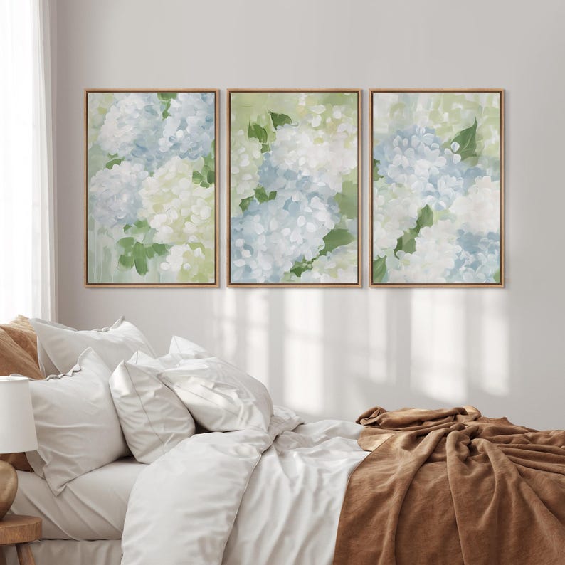Puede incluir: Tres impresiones art&iacute;sticas florales enmarcadas. Cada impresi&oacute;n presenta flores de hortensia en tonos azules, blancos y verdes. La obra de arte est&aacute; sobre un fondo verde claro, con un marco de madera natural.