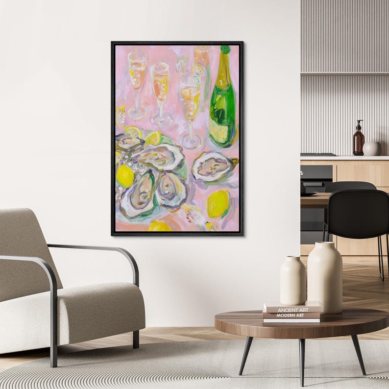 May include: An abstract painting of a still life featuring oysters, lemons, champagne glasses, and a bottle of champagne. The artwork has a pink background and is framed in black. The oysters are open, and the lemons are yellow.