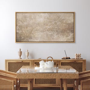 May include: A rectangular landscape wall art piece featuring a muted, sepia-toned illustration of tree branches and foliage. The artwork is enclosed in a thin, metallic gold frame, displaying a soft, atmospheric depiction of nature in neutral tones.