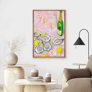 May include: An oil painting on canvas depicts a still life of oysters, champagne, and lemons. The artwork features a pink background, a green champagne bottle, and several champagne flutes. The oysters are arranged on a plate with lemon wedges.