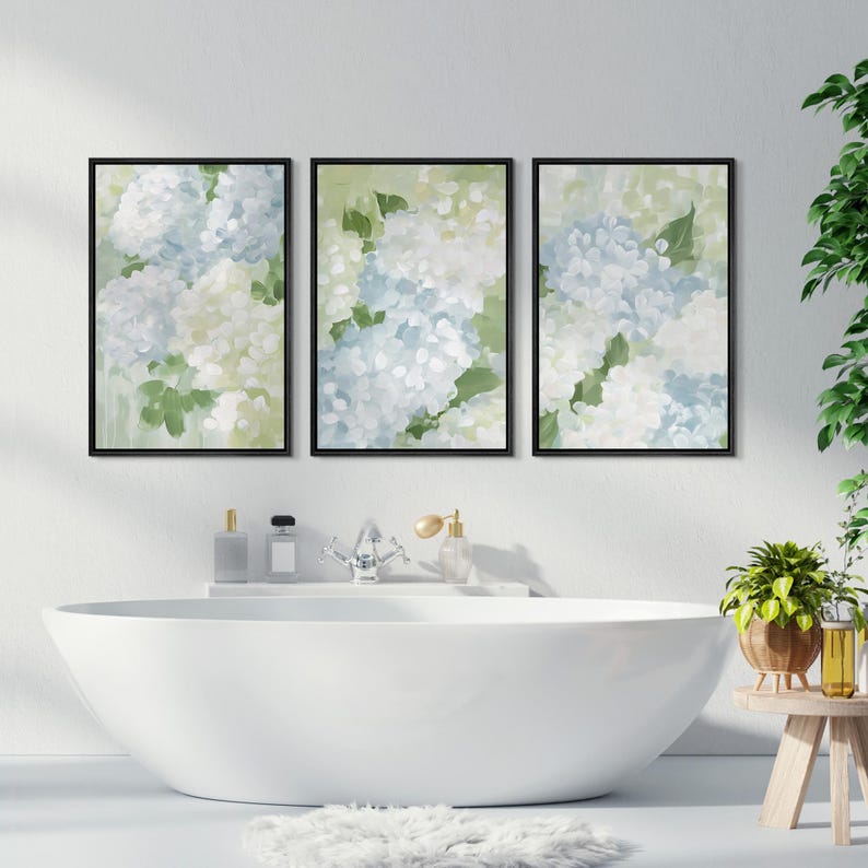Puede incluir: Conjunto de tres l&aacute;minas art&iacute;sticas florales enmarcadas. Cada l&aacute;mina presenta una pintura al estilo acuarela de flores de hortensia en tonos azules, blancos y verdes. Los marcos negros se exhiben sobre una ba&ntilde;era blanca.