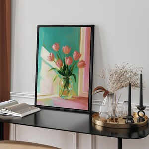 Pu&ograve; includere: Dipinto incorniciato di tulipani rosa in un vaso di vetro trasparente, su sfondo turchese e rosa. L'opera &egrave; esposta su un tavolo nero, con candele e un vassoio decorativo.