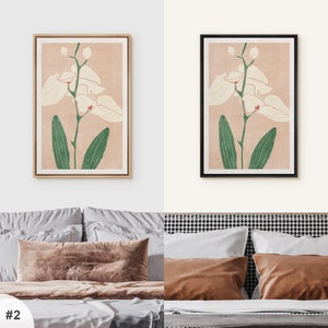 Pu&ograve; includere: Due stampe incorniciate di un'orchidea bianca con foglie verdi su uno sfondo rosa chiaro. Le cornici sono diverse, una &egrave; in legno e l'altra &egrave; nera.
