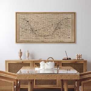 May include: A vintage map print in a wooden frame, hanging on a white wall above a wooden table with a white teapot and two decorative vases.