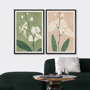 Pu&ograve; includere: Due stampe incorniciate di fiori di orchidea bianchi con foglie verdi su uno sfondo verde chiaro e rosa chiaro.