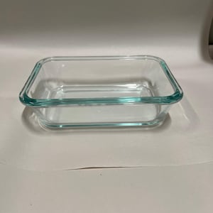 Peut inclure: Un plat de cuisson rectangulaire en verre transparent avec des coins arrondis et un bord épais et lisse. Le récipient présente des parois transparentes et une base plate, conçu pour le stockage des aliments ou une utilisation au four.