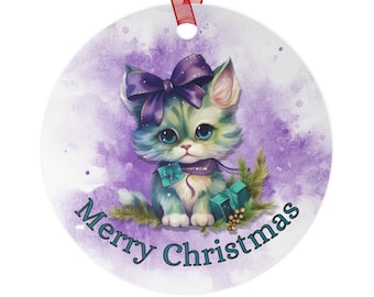 May include: A purple and green watercolour Christmas bauble featuring a cute cartoon kitten wearing a purple bow and holding a teal gift box. The bauble says "Merry Christmas" in teal lettering.