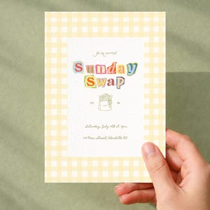 Op de afbeelding: Een rechthoekige uitnodigingskaart met een lichtgele en witte gingham-rand. In het midden staat de tekst "You're invited!", "Sunday Swap", "EST '06", "Saturday, July 10th at 4pm" en "123 Main Street, Charlotte NC" met een lijntekening van een tas.