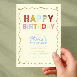 May include: A cream-colored birthday invitation card with a gold wavy border. The text reads HAPPY BIRTHDAY in multi-colored patterned letters, followed by JOIN US FOR Olivia's 2ND BIRTHDAY! JUNE 20, 2026 AT 1PM THE NORTH PARK 123 MAIN ST, MAIDSON WI.