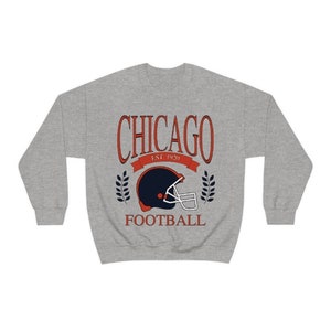 May include: A gray sweatshirt with a vintage-style graphic of a football helmet and the text "CHICAGO EST. 1920 FOOTBALL".