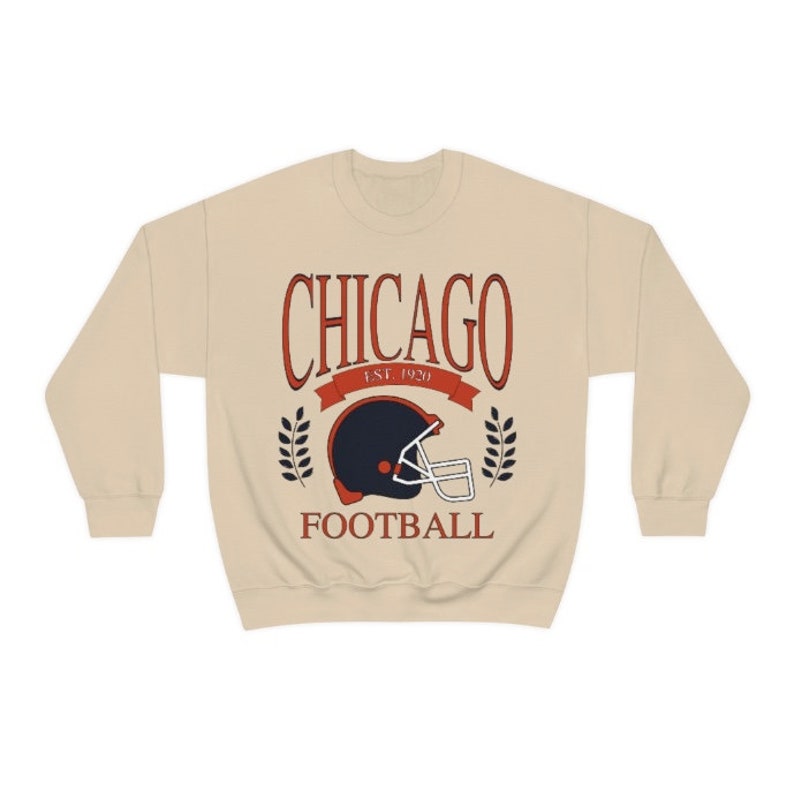 May include: A beige sweatshirt with a vintage-style graphic of a football helmet and the text "CHICAGO EST. 1920 FOOTBALL".