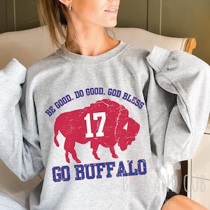 May include: A gray sweatshirt with a red buffalo graphic and the number 17 in white. The text "BE GOOD. DO GOOD. GOD BLESS" and "GO BUFFALO" are in blue.