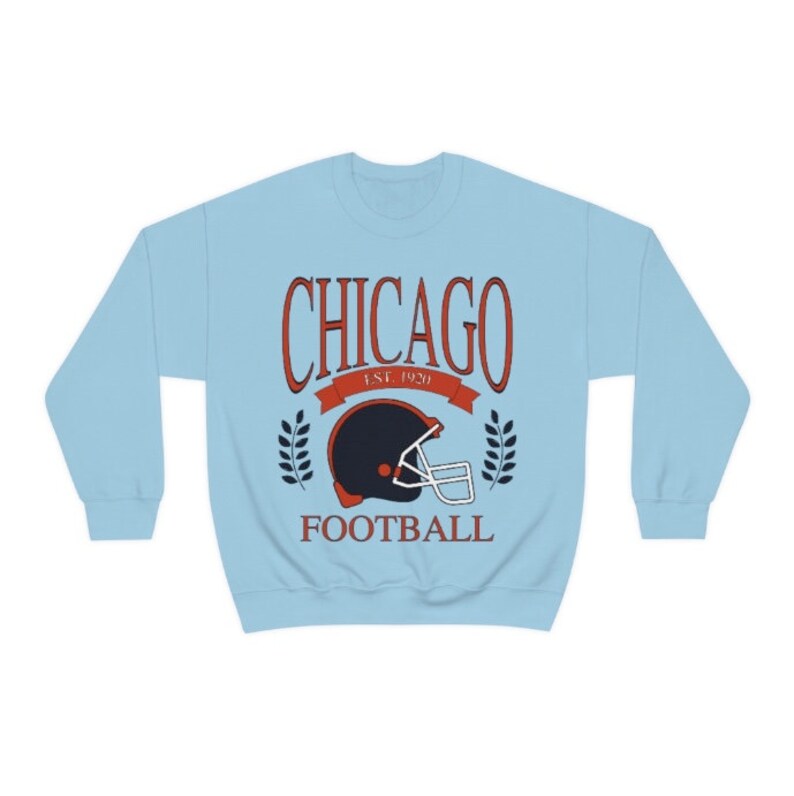 May include: Light blue sweatshirt with a vintage-style graphic of a football helmet and the text "CHICAGO EST. 1920 FOOTBALL".
