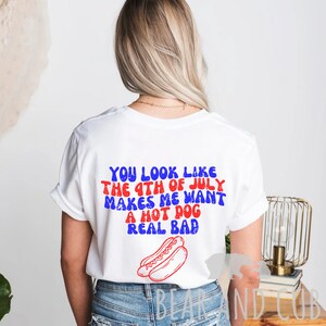 May include: White t-shirt with red and blue text that reads "You look like the 4th of July makes me want a hot dog real bad". A red and white hot dog is pictured below the text.