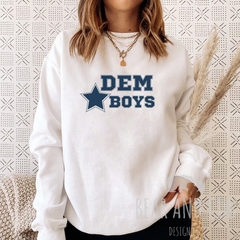 May include: White sweatshirt with a blue star and the text "DEM BOYS" in navy blue letters.