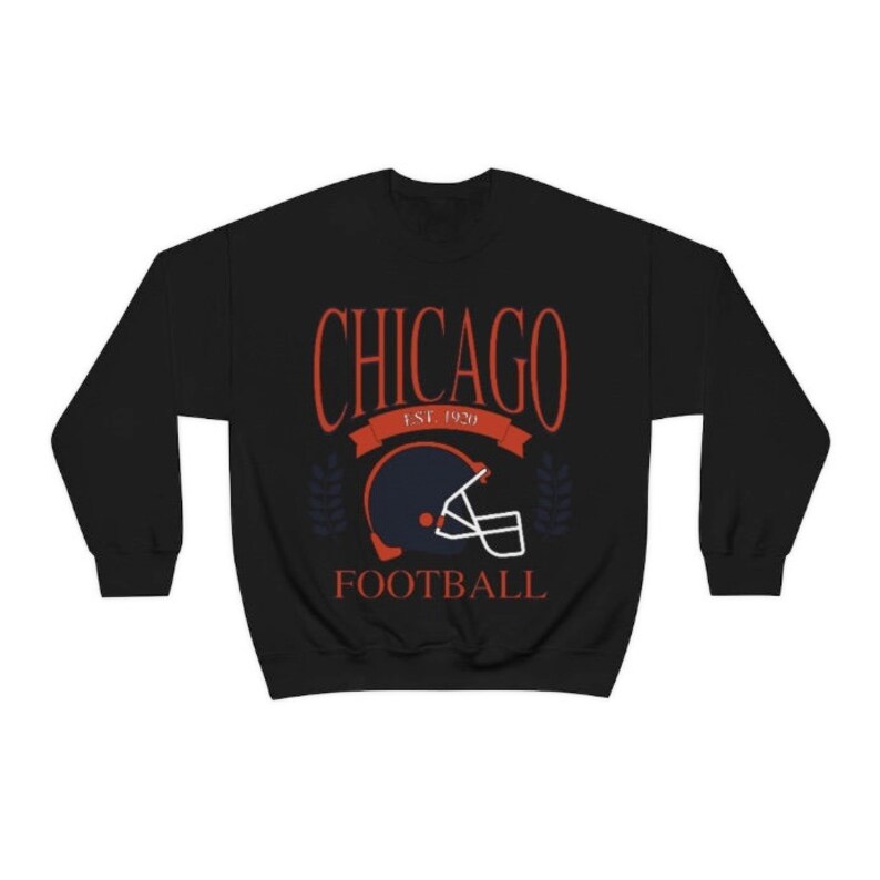 May include: Black sweatshirt with a red and white graphic design that says "CHICAGO EST. 1920 FOOTBALL" with a blue and orange football helmet in the center.