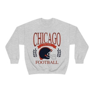 May include: A gray sweatshirt with a red and blue graphic design. The graphic features a football helmet with the text "CHICAGO EST. 1920 FOOTBALL".