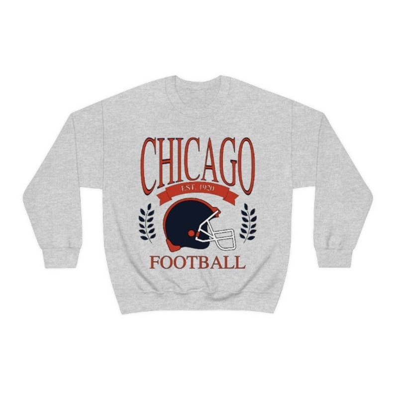 May include: A gray sweatshirt with a red and blue graphic design. The graphic features a football helmet with the text "CHICAGO EST. 1920 FOOTBALL".
