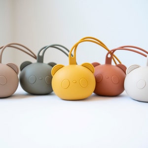 May include: Five silicone baby teethers in different colors, shaped like a bear with a cute face. The teethers have a loop for hanging.