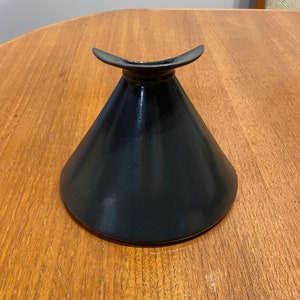 Peut inclure: Un vase en céramique noire avec une base large et évasée et un sommet étroit et incurvé.