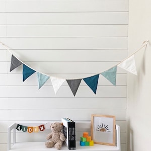 Blue linen bunting decoration for nursery on top of kid's bookcase