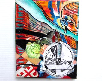 May include: Abstract painting on canvas with a colorful, geometric design. The painting features a stylized face, circles, and a black and white geometric pattern.