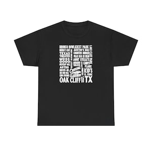 May include: A black short-sleeve t-shirt featuring a white graphic print on the chest. The design consists of a list of various local landmarks and businesses in Oak Cliff, Texas, arranged in a block format with a small car illustration.