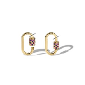 May include: Two gold-coloured, oval-shaped earrings, each featuring a cylinder encrusted with colourful gems. The earrings are designed to look like padlocks. The brand name "BAWREEJEWELS" is printed on the top of each earring.