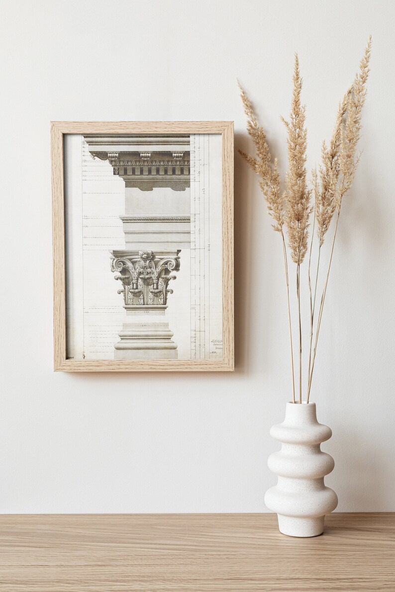 May include: A framed print of a detailed architectural drawing of a column capital, with a vase of dried pampas grass in the foreground.