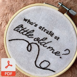 Pode incluir: Um aro de bordado branco com um desenho bordado preto que diz "quem tem medo do velhote?"