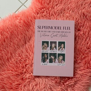Op de afbeelding: Een roze boek getiteld "Supermodel Fuel: The Secret Diet and Daily Rituals of Victoria's Secret Models" met foto's van modellen op de omslag.