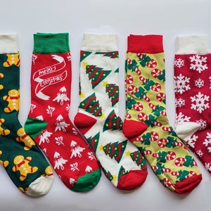 May include: Six pairs of Christmas themed socks. The socks are red, green, and white with various Christmas designs including candy canes, snowflakes, gingerbread men, and Christmas trees. The socks have a white cuff.
