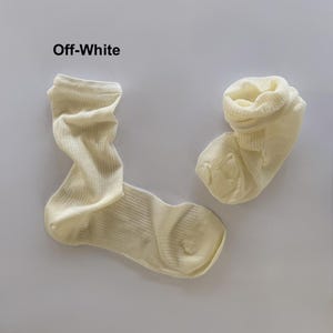 May include: Two off-white socks are shown against a white backdrop. The socks are made of a ribbed knit material. The text "Off-White" is above the socks.